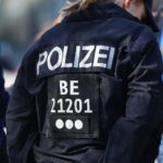 Polizistin vor Einsatzfahrzeug, Symbolbild der Festnahme eines Tatverdächtigen in Berlin.
