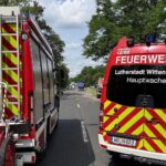 Schwerer Verkehrsunfall: Einsatzkräfte befreien eingeklemmten Fahrer, Rettungshubschrauber auf Wiese vorbereitet.