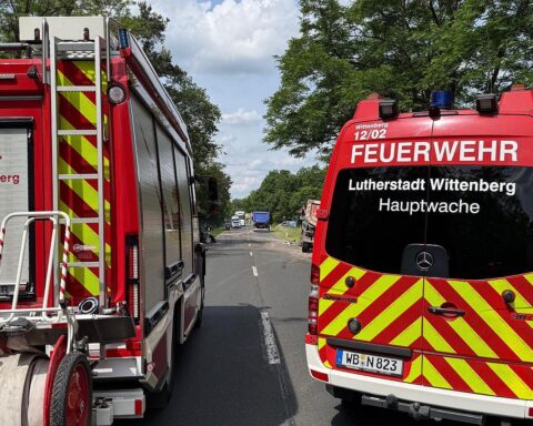 Schwerer Verkehrsunfall: Einsatzkräfte befreien eingeklemmten Fahrer, Rettungshubschrauber auf Wiese vorbereitet.