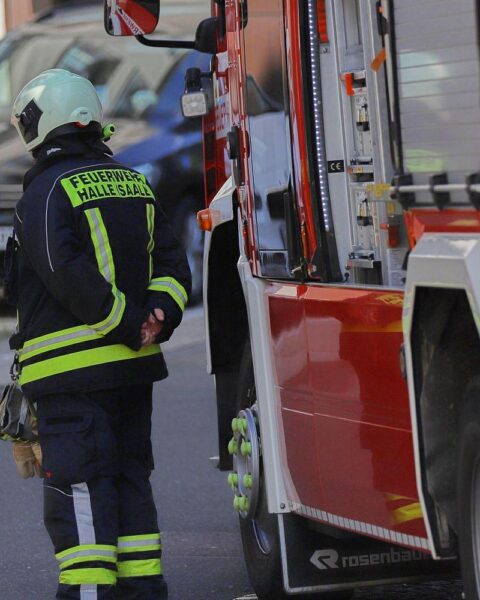 Einsatzkräfte der Feuerwehr sichern Unfallstelle, Radfahrer verletzt, Straßenbahn im Hintergrund.