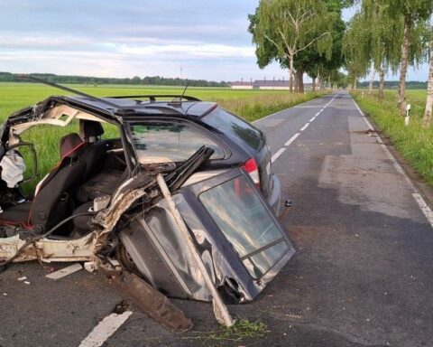 Unfallstelle mit beschädigtem Auto und mehreren Straßenbäumen, Rettungskräfte vor Ort.