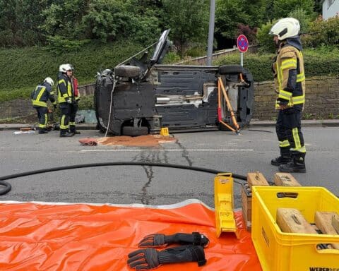 PKW-Unfall mit Straßenlaterne; Fahrzeug umgekippt, Feuerwehr im Einsatz zur Rettung des Fahrers.