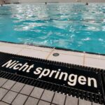 Ein Schwimmbad mit Kindern, Sicherheitsvorkehrungen sowie ein Hinweis auf Schwimmabzeichen.