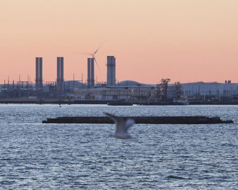Industrieanlagen und Maschinen, die Energieerzeugung und -speicherung symbolisieren, im Hintergrund modernes Bürogebäude.