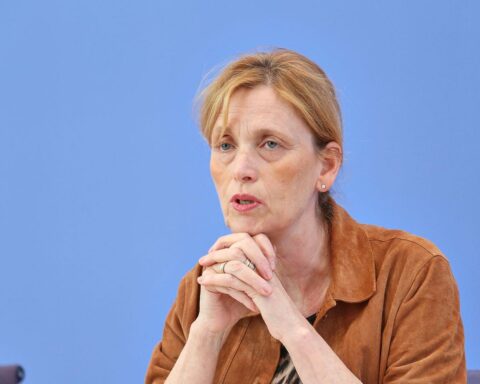 Karin Prien in Berlin, umgeben von Symbolen für Demokratie und kommunale Partnerschaften.