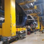 Eine Montage von Autos in einer Fabrikhalle, symbolisiert Optimismus und Herausforderungen der Automobilindustrie.