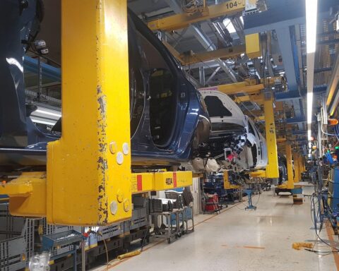 Eine Montage von Autos in einer Fabrikhalle, symbolisiert Optimismus und Herausforderungen der Automobilindustrie.