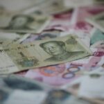 Chinesische Geldscheine neben Grafiken zu BIP und Handelsbilanzdefizit zwischen Deutschland und China.