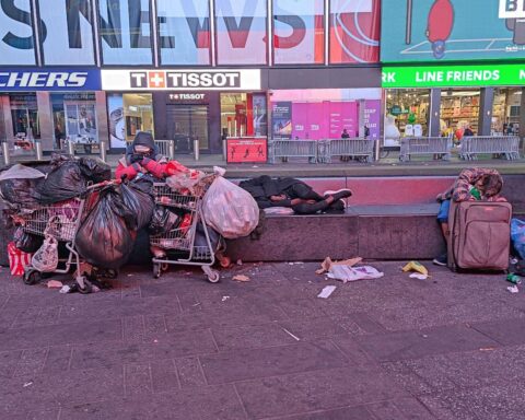 Obdachlose Menschen am Times Square, symbolisieren soziale Probleme trotz stabiler Arbeitsmarktzahlen in den USA.