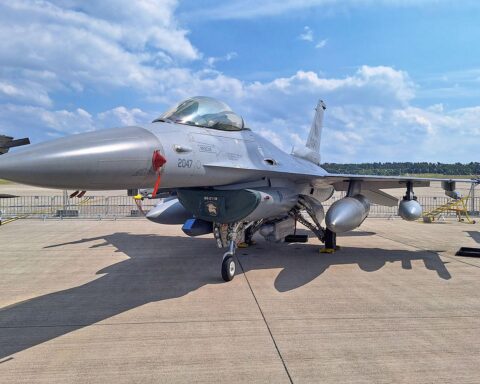 F-16 Kampfjet vor Militärhintergrund, symbolisiert zeitgemäße Verteidigung und geopolitische Herausforderungen.