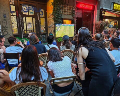Fußballfans sehen gemeinsam auf der Straße ein Spiel während der Weltmeisterschaft 2026.