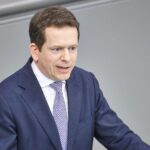 Martin Plum bei einer Diskussion, umgeben von politischen Symbolen der CDU und Bundestag.