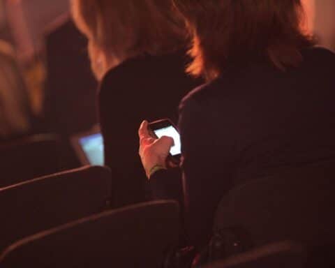 Geschäftsfrauen diskutieren mit Smartphones über Entgelttransparenzrichtlinie und Gleichberechtigung in der Arbeitswelt.