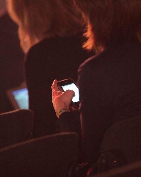 Geschäftsfrauen diskutieren mit Smartphones über Entgelttransparenzrichtlinie und Gleichberechtigung in der Arbeitswelt.
