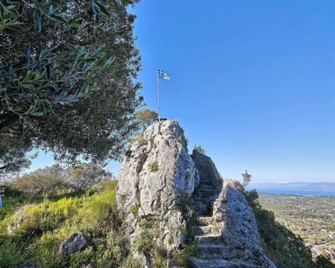 Griechische Fahne weht im Wind, symbolisiert günstigen Urlaub und schöne Reiseziele in Südeuropa.