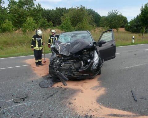 Unfallfahrzeuge auf Bundesstraße, Polizei vor Ort, Verletzte werden behandelt, Sachschaden ermittelt.