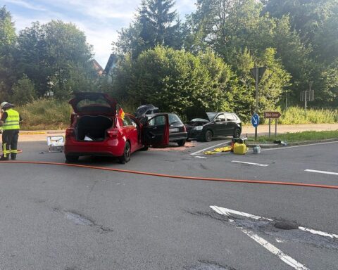 Unfallstelle mit drei PKW, Rettungsdienste im Einsatz, verletzte Personen, gesperrte Fahrbahn.