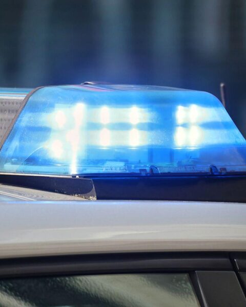 Unfallstelle mit Polizei, zerstörtem Fahrzeug und Absperrband, symbolisiert Tragödie auf Landstraße.