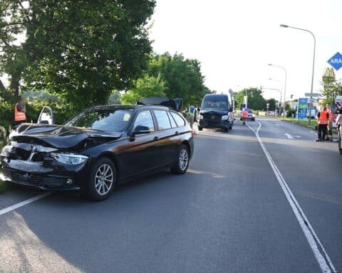 Unfallstelle mit mehreren Fahrzeugen, Rettungsdiensten und Feuerwehrkräften, abgesperrte Straße.