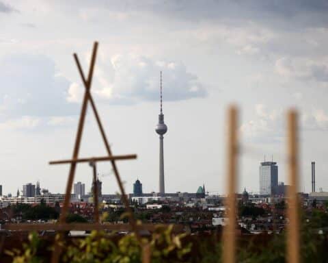 Dachterrasse in Berlin mit Blick auf den Fernsehturm und bewölkten Himmel.