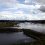 Eine ruhige Flusslandschaft mit wetterveränderlichen Wolken über der Oder zwischen Deutschland und Polen.