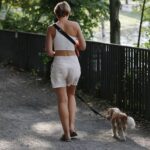 Frau mit Hund im Park, während extreme Hitze und Gewitterwarnung gemeldet werden.