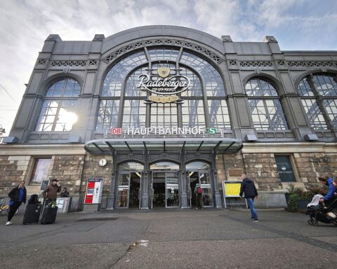 Sonniger Dresden Hauptbahnhof bei wechselhaftem Wetter, mit Wolken und Nebel im Hintergrund.
