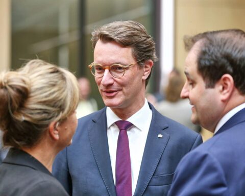 Drei Politiker stehen zusammen vor einem Gebäude und diskutieren über europäische Wirtschaftsthemen.