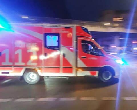 Rettungswagen an Unfallstelle mit stark beschädigtem Fahrzeug und Feuerwehr im Einsatz.