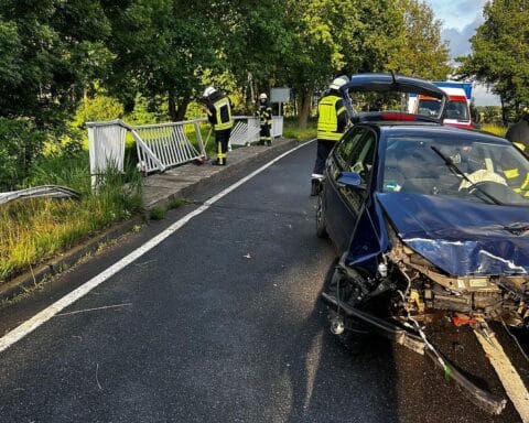 Verunfallter VW Polo gegen Brückengeländer, Einsatzkräfte sichern Unfallstelle und versorgen Verletzte.