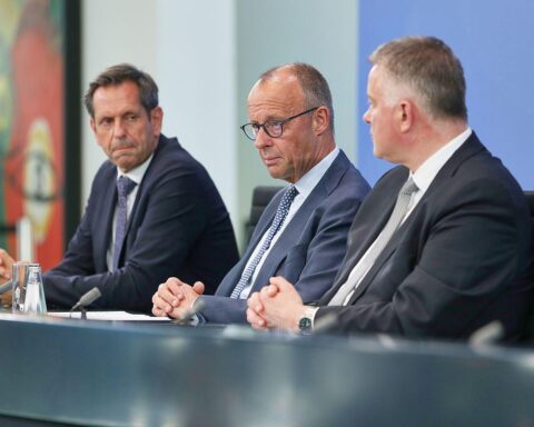 Politiker Merz, Lies und Schnieder diskutieren Finanzreform und Infrastrukturmaßnahmen auf Konferenz.