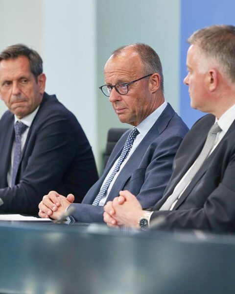 Politiker Merz, Lies und Schnieder diskutieren Finanzreform und Infrastrukturmaßnahmen auf Konferenz.