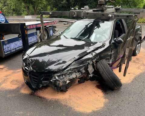 Stark beschädigter Alfa Romeo nach Unfall an Leitplanken; Einsatzkräfte und abgeschlepptes Fahrzeug.