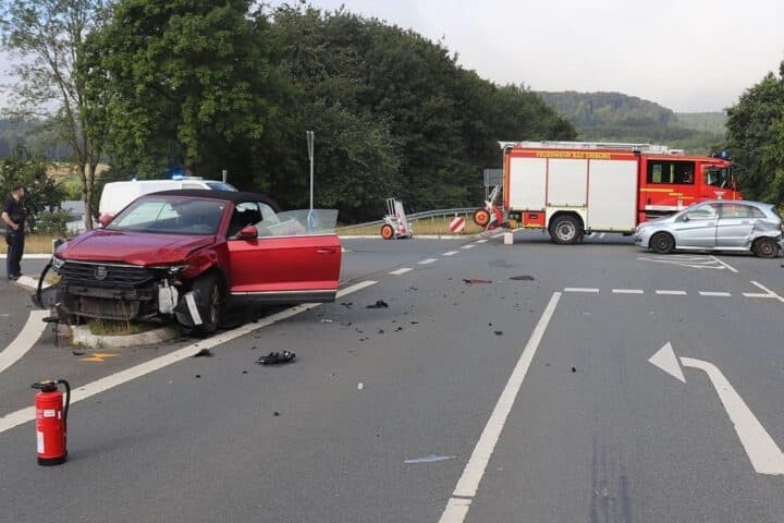 Unfall auf der B64 bei Bad Driburg: zwei kollidierte Autos, Verkehrsinsel beschädigt, Polizei am Einsatzort.