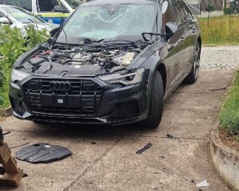 Zerstörter Audi A6 nach Sprengstoffanschlag, Motorhaube abgerissen, massive Schäden sichtbar.