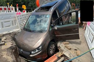 Verunfallter Pkw in Baugrube, Einsatzkräfte und Absperrung sichtbar; Unfallstelle in Niederfell.