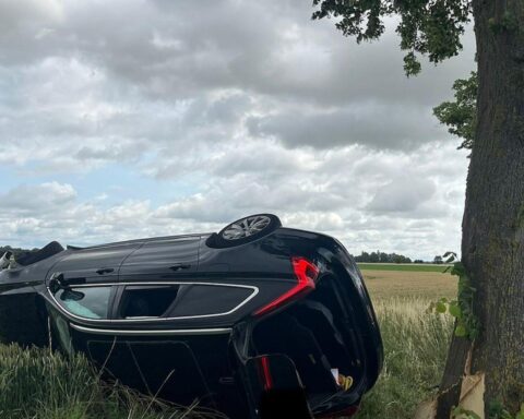 Verkehrsunfall: Umgestürzter Volvo, Polizei und Rettungswagen am Unfallort, beschädigtes Fahrzeug auf Feld.