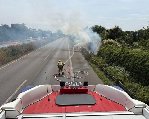 Flächenbrand an A57 in Moers: Feuerwehr löscht, Verkehr stark behindert, Rauchentwicklung sichtbar.