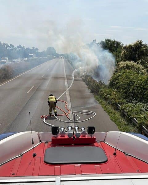 Flächenbrand an A57 in Moers: Feuerwehr löscht, Verkehr stark behindert, Rauchentwicklung sichtbar.