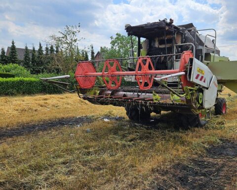 Mähdrescher brennt, Feuerwehr löscht Brand auf Feld, Fahrer in Sicherheit gebracht.