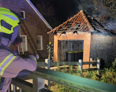 Feuerwehr löscht Garagenbrand, der angrenzendes Mehrfamilienhaus bedrohte; Einsatzkräfte im Einsatz.