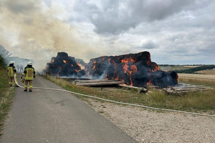 Mehrere brennende Heuballen bei einem Sportplatz in Tiefenbach, Feuerwehr im Einsatz, Archivfoto.