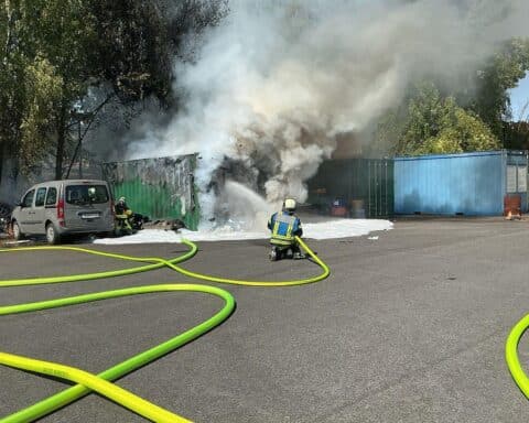 Feuerwehr löscht Brand von zwei Überseecontainern in Bochum-Wattenscheid, starke Rauchsäule über der Lohrheidestraße.