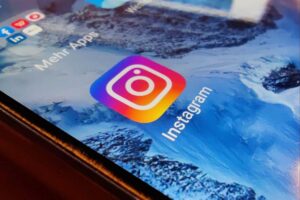 Smartphone zeigt Instagram-Logo; Kritik an Meta's Design für süchtig machende Nutzererfahrungen.