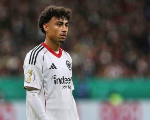 Nathaniel Brown, jubelnd im FC Bayern Trikot, symbolisiert seinen Wechsel von Frankfurt nach München.