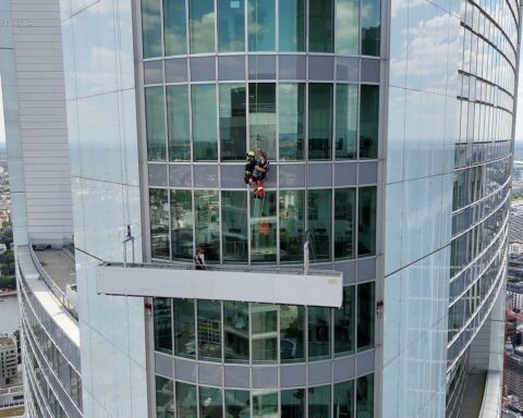 Zwei Fassadenreiniger werden aus Korb in großer Höhe von Feuerwehr mit Seilwinde gerettet.