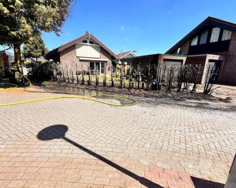 Feuerwehr löscht Heckenbrand, schützt Garage; Einsatzkräfte arbeiten schnell und entscheidend.