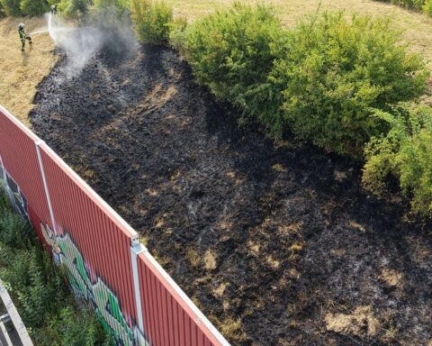 Feuerwehr löscht Böschungsbrand an der A40; Einsatzkräfte mit Schläuchen und Drohne im Einsatz.