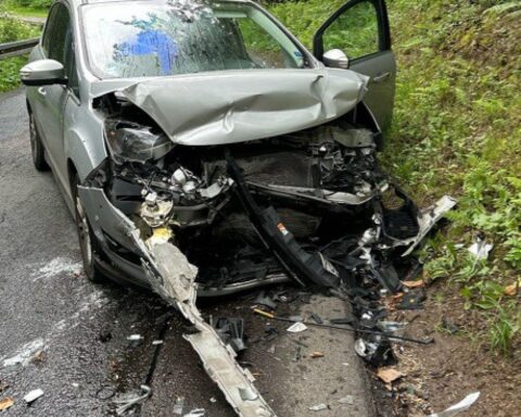 Zwei verunfallte Autos im Kurvenbereich, Polizei und Rettungsdienst vor Ort, Unfallstelle abgesperrt.