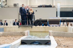Wissenschaftler erklären Hochwasserschutz. Politiker und Experten beobachten Wasserstau am Brückenmodell.